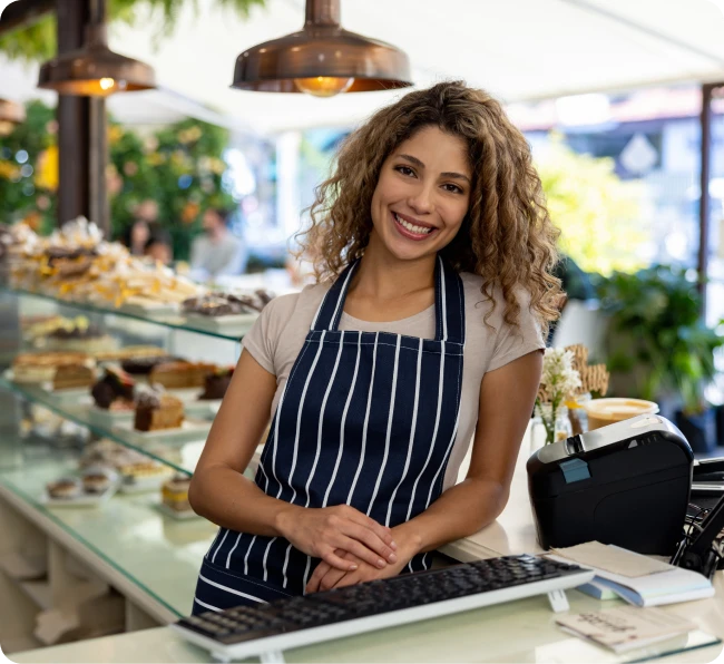 A smiling business owner behind the counter of her café